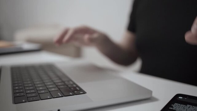 Multitasking Man Browsing Smartphone While Working on Laptop