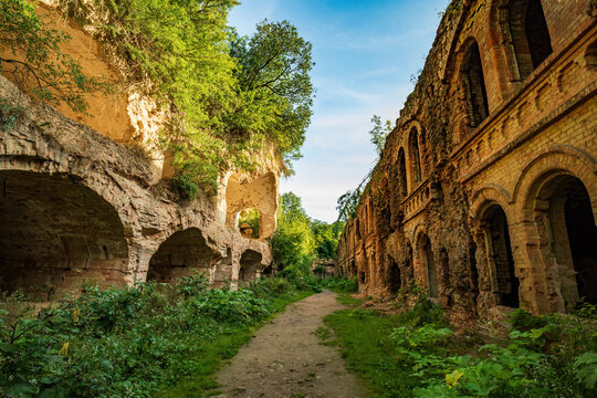 Tarakaniv Fort ruins near Dubno, Rivne region, Ukraine, showcasing ancient brick and stone architecture with arched forms and overgrown vegetation under a blue sky