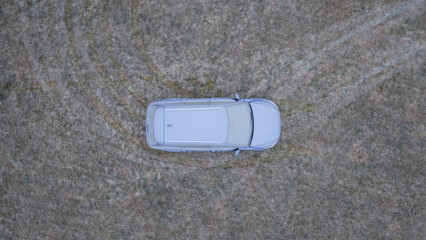 Aerial View of a Frost-Covered Car on Frozen Grass During an Icy Winter Morning.