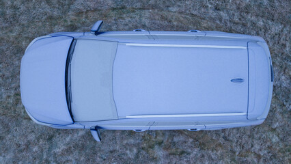 Aerial View of a Frost-Covered Car on Frozen Grass During an Icy Winter Morning.