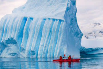 extreme adventure travel, people kayaking in Antarctica, iceberg and red kayak © Song_about_summer
