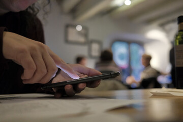 Gros plan sur une femme utilisant son t&eacute;l&eacute;phone portable intelligent dans un caf&eacute;.