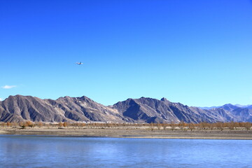 airplane approaching Lhasa, Tibet, China over the Yarlung Tsangpo River, upper reaches of the Brahmaputra, with high level mountain background
