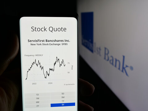 Stuttgart, Germany - 12-12-2025: Person holding cellphone with webpage of US bank ServisFirst Bancshares Inc. on screen in front of logo. Focus on center of phone display.