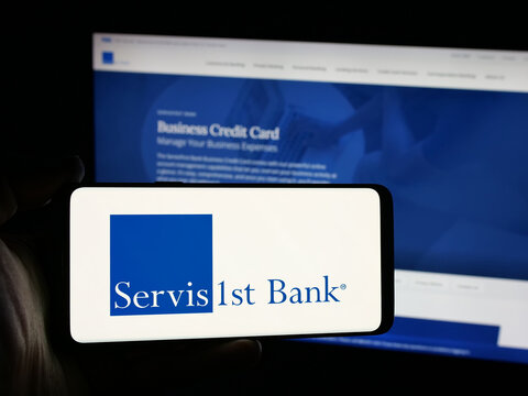 Stuttgart, Germany - 12-12-2025: Person holding smartphone with logo of US bank ServisFirst Bancshares Inc. on screen in front of website. Focus on phone display.