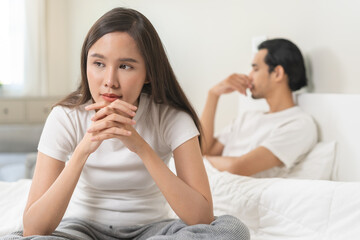 Angry, depressed, frustrated asian couple quarrel, fighting on bed in conflict, divorce or...
