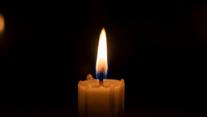 Single candle flame in darkness