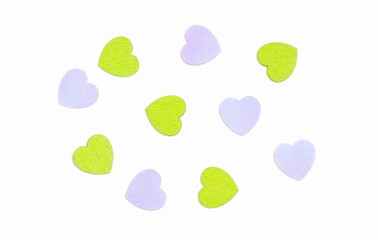 scattered wooden purple and green hearts isolated on white background, top view