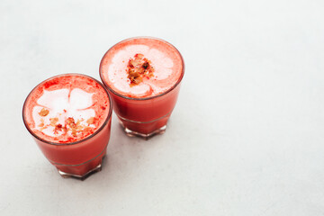 Two trendy beetroot lattes with latte art and flower petals on the foam.