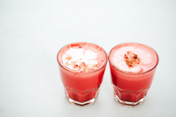 Two trendy beetroot lattes with latte art and flower petals on the foam.