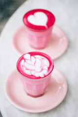 Two trendy beetroot lattes with latte art and flower petals on the foam.
