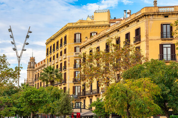 Facades of classic buildings in the port district of Barcelona with multiple balconies and iron grilles, Spain.
