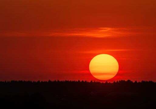 A deeply saturated, surreal sky explodes in vibrant orange and red hues, featuring a massive, intensely glowing sun sphere near the horizon ,atmospheric ,vivid ,atmosphere