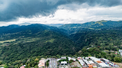 Panoramic Aerial View of Lush Mountain Forest and Industrial Zone Under Stormy Sky