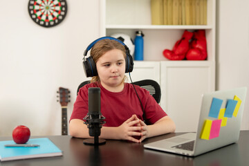 Kid recording podcast episodes with headphones. Young digital creator working on podcast. Child podcaster speaking into studio mic. Creative kid using microphone for digital projects.