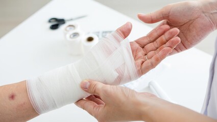 Rehab clinic close-up therapist wrapping bandage on injured wrist, clean medical setting photo