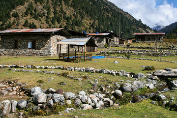 Traditional Bhutan Himalayan village in mountain valley with stone houses, tin roofs, solar panels,...