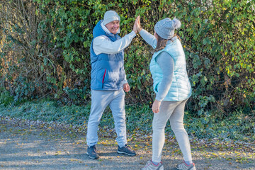 plus size woman and senior man giving high five on park path, Happy couple running playfully, successful workout together, outdoors healthy and active lifestyle, positive energy, winter fitness