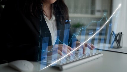 A businesswoman types on a keyboard while analyzing data trends through a graph visualization in a modern office, highlighting the importance of digital analytics in business growth. Copula
