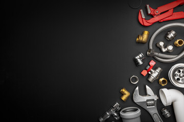 Plumbing tools and fittings on black background with copy space. Plumber equipment