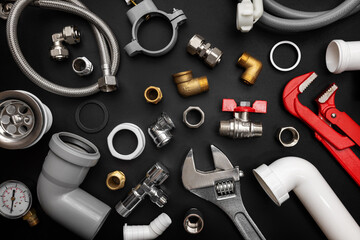 Plumbing tools and fittings on black background. Plumber equipment, top view