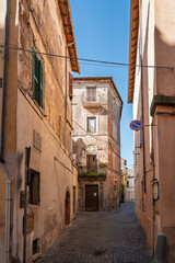  Italy - Sutri - Historic center - Narrow cobbled alley with plastered houses, balconies, plants and soft afternoon light