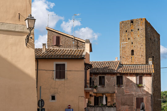 Italy - Sutri - Historic center - Medieval tower and houses near cathedral seen across narrow street and ochre facades