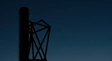 A black industrial tower reaching towards a blue dusk sky, showcasing structural silhouette.