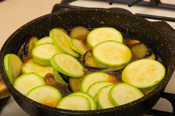 Zucchini cut into rings are fried in a frying pan in oil