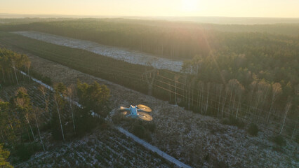 Drone flight over a high-voltage electricity pylon at sunset during winter.
