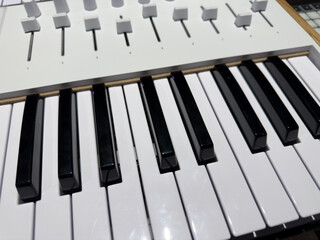 Close up photo of white and black keys on electric synthesizer with volume controls. Adjusting volume on synthesizer during virtuoso playing. Concept of electronic music and keyboard instrument