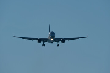 Fototapeta premium Silhouette of Commercial Airplane Approaching Runway for Landing Against Clear Blue Evening Sky