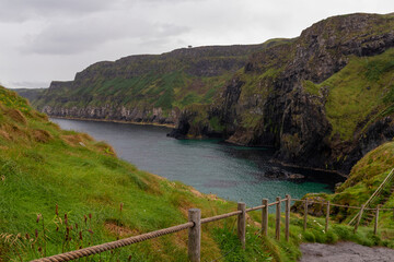 the famous hiking path to the bridge at the Carrick a rede coastline in north ireland at a cloudy summer day