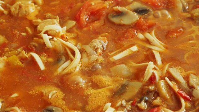 Vegetables with chicken and udon noodles are stewed in a frying pan in Pad Thai sauce