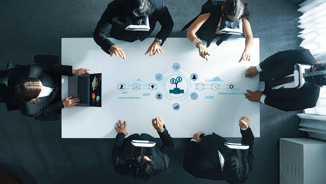 A dynamic business meeting featuring professionals wearing virtual reality headsets in a modern office setting, engaged in collaborative digital project development and strategic planning. Trope - Powered by Adobe