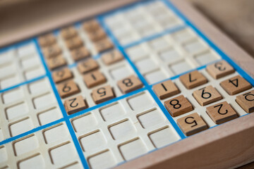 closeup hands carefully placing number into Sudoku puzzle, senior man focused on solving puzzle on wooden board, Brain exercise, cognitive health, and mental agility in mature age, brain health