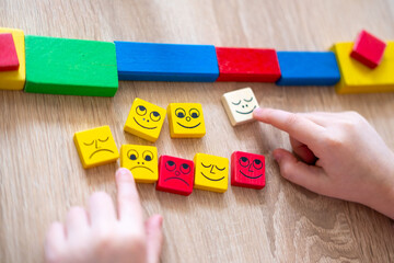 Wooden blocks with emotions, Child's hand playing with wooden blocks. Different emotions displayed on blocks. Educational toy concept