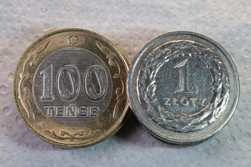 Kazakhstan Tenge and Polish Zloty Coin Comparison. Close-up photo of Kazakhstani 100 tenge coin placed next to a Polish 1 zloty coin. The image illustrates comparison of national currencies, exchange 