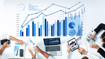 A dynamic business team collaborates to analyze financial data using charts and digital devices, showcasing teamwork and data-driven decision-making in a modern workspace. Scalp