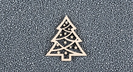 A wooden cutout of a Christmas tree adorned with stars rests atop a surface of countless tiny, dark spheres
