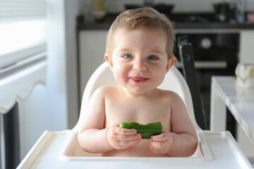 Baby eating cucumber. Copy space, background.