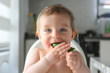 Baby eating cucumber. Copy space, background.