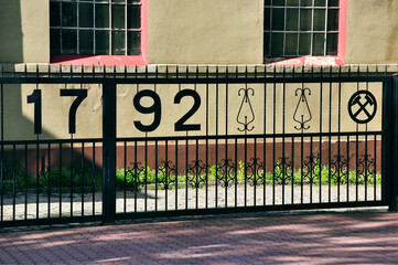 Kopalnia Węgla Kamiennego Rydułtowy - Przed budynkiem zabytkowe żelazne ogrodzenie z datą 1792 r. i ozdobnymi symbolami górniczymi. © Pol Badger