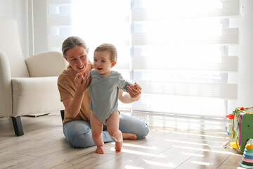 Mom assisting her baby in learning to walk. Copy space, background.
