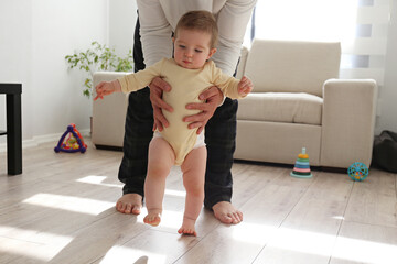 Father helping a baby to learn how to walk. Copy space, background.
