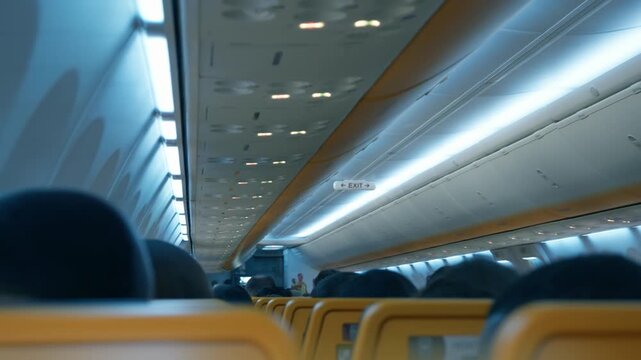 Commercial airplane cabin interior shakes and vibrates due to heavy turbulence during night flight. Passengers sit in rows experiencing stress and aerophobia while aircraft encounters rough weather.