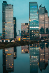 Fototapeta premium big city skyline at sunset with mirrored water reflection, modern high-rise skyscrapers at golden hour urban dusk, downtown mirroring on swimming pool, Bangkok Thailand