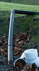 Black drainage pipe and white PVC fitting in grassy construction area