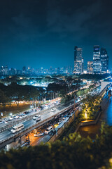 Fototapeta premium illuminated big city skyline at night, cars on road at rush hour, Lumpini park with festive street lights, high-rise skyscrapers and downtown glow at evening, Dusit Central, Bangkok Thailand