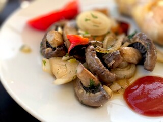 Lunch Food With Mushrooms, Onions, and Peppers Served on a Plate in a Cafe Setting